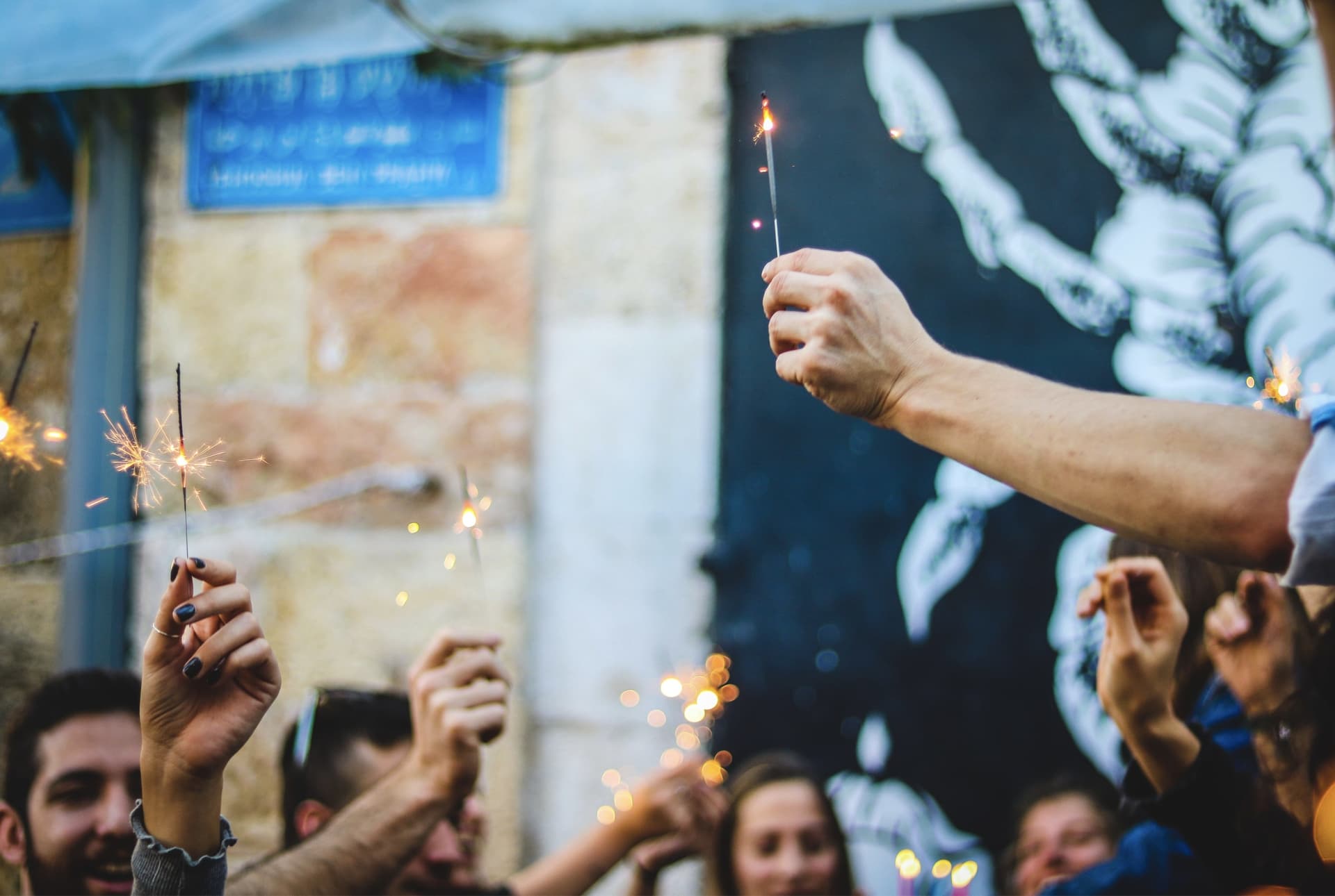 People are holding sparklers while celebrating birthday in the company.